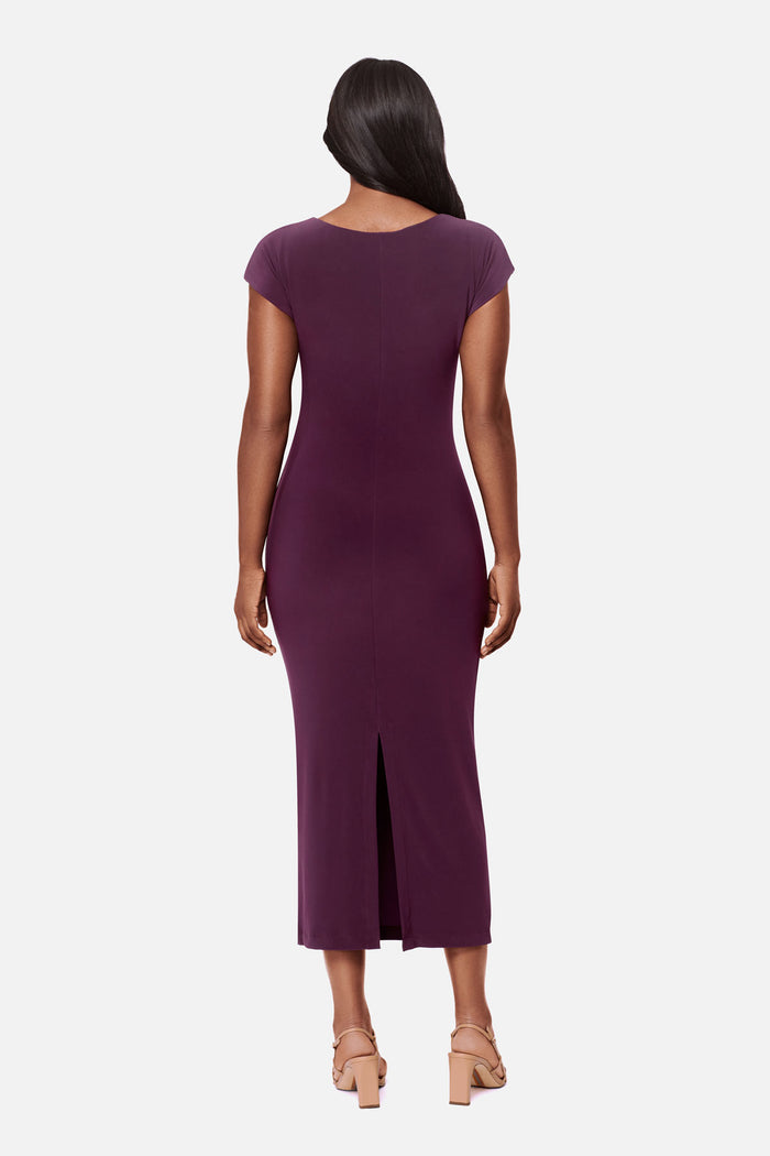 Woman turned away wearing a dark purple short sleeve dress with a gold tone hardware detail on the side