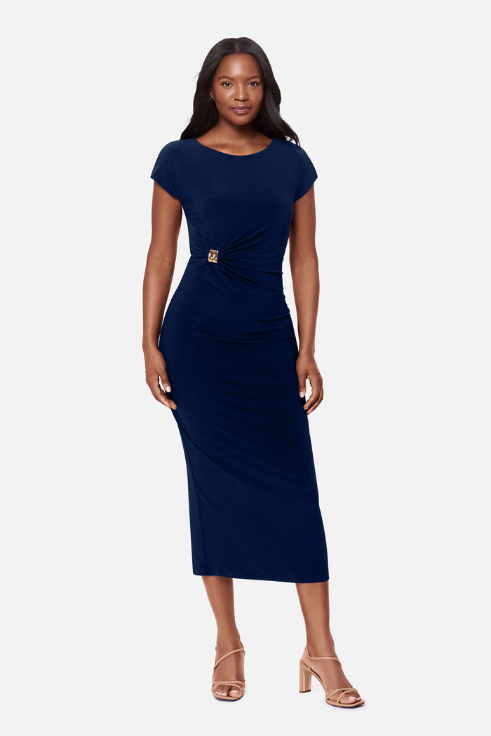 Woman wearing a navy-blue short sleeve dress with a gold tone hardware detail on the side