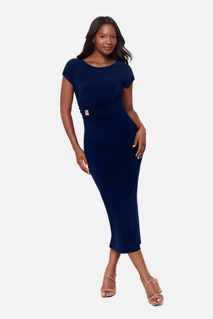 Woman wearing a navy-blue short sleeve dress with a gold tone hardware detail on the side