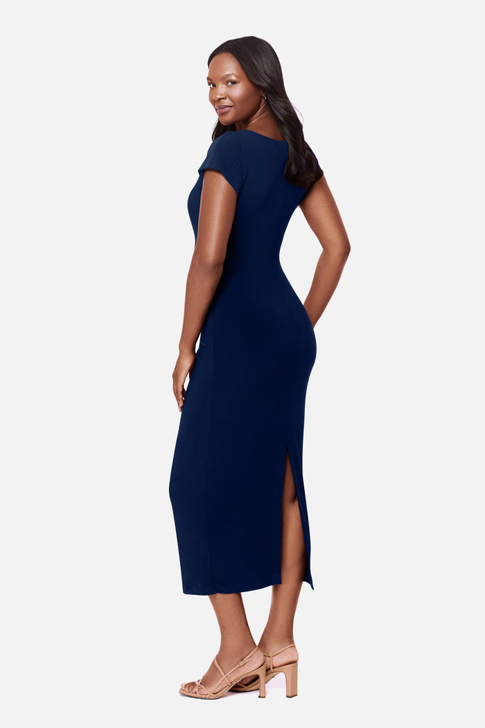 Woman turned left wearing a navy-blue short sleeve dress with a gold tone hardware detail on the side