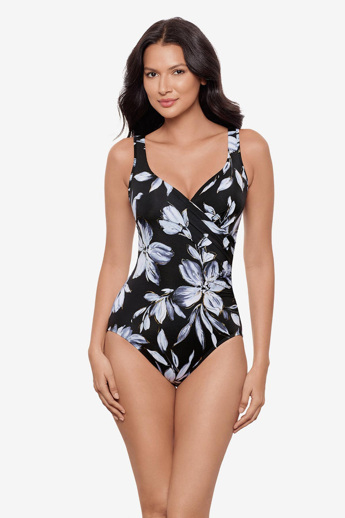 Woman wearing a black and white floral printed one-piece swimsuit with a sweetheart neckline