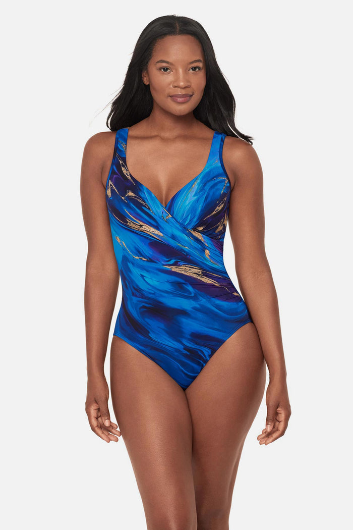 Woman wearing a blue and gold oil slick-esque printed one-piece swimsuit