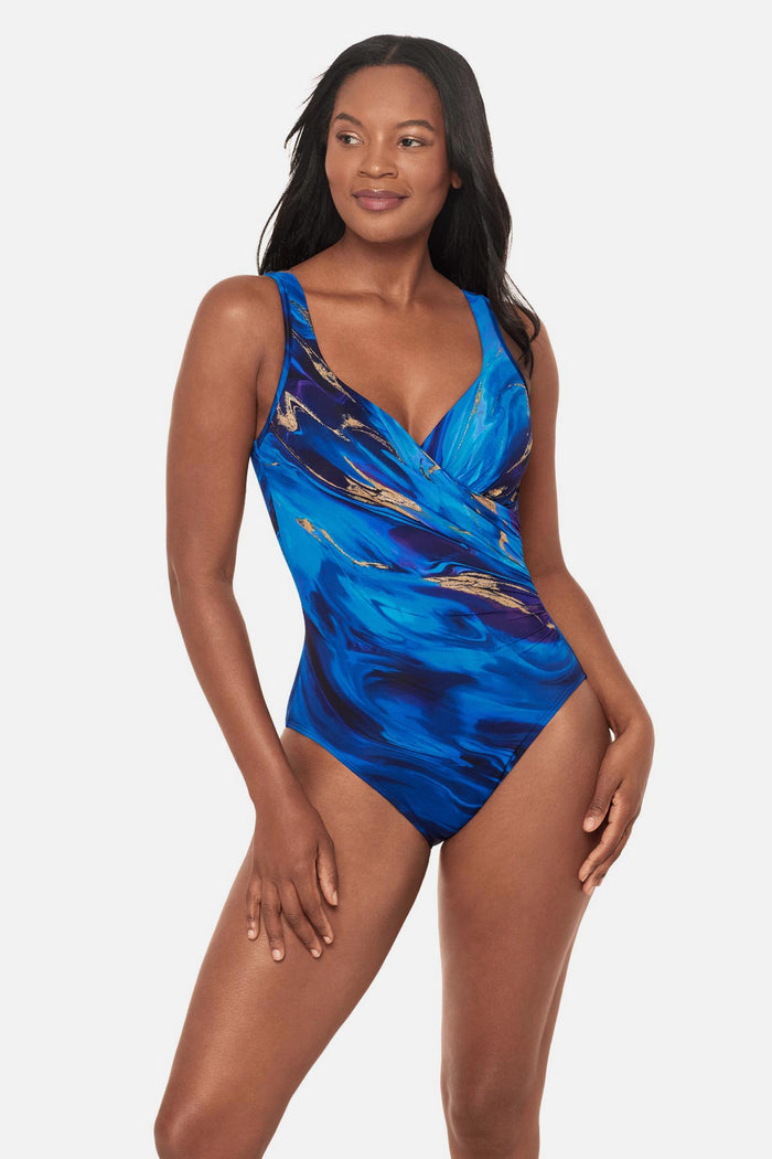 Woman wearing a blue and gold oil slick-esque printed one-piece swimsuit