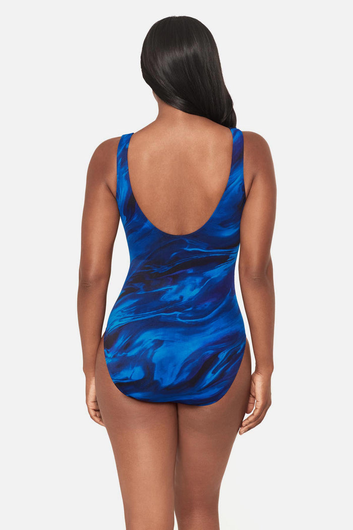 Woman faced away wearing a blue and gold oil slick-esque printed one-piece swimsuit