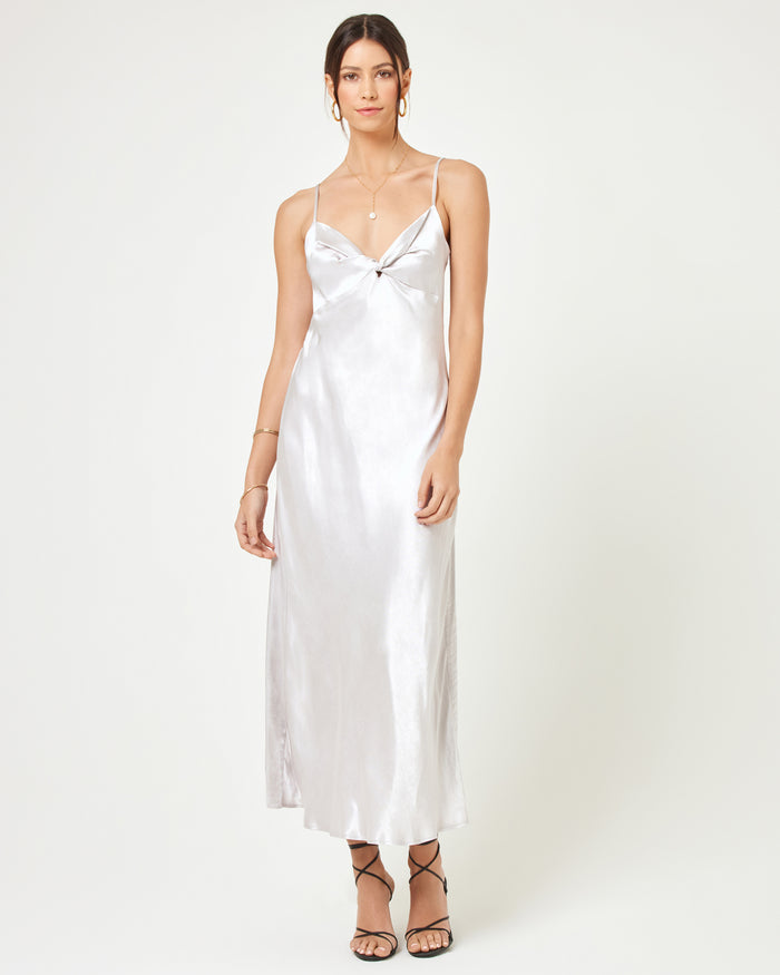 Front view of a model wearing the LSPACE Joanna Dress in silver, featuring the full-length satin slip silhouette with V-neckline, thin spaghetti straps, and twisted knot detail at the bust.