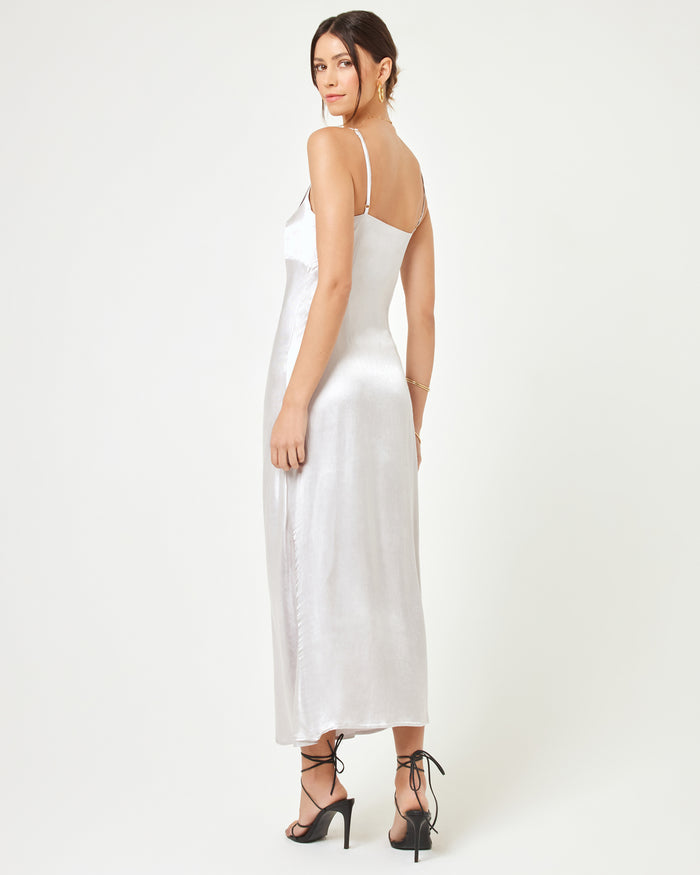 Back view of a model wearing the LSPACE Joanna Dress in silver, showing the low scoop back, thin spaghetti straps, and fluid drape of the silver satin slip maxi dress.