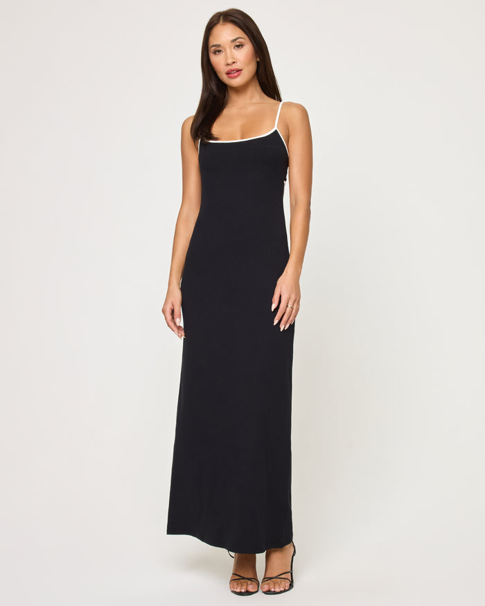 Full-length front view of a model wearing the LSPACE Jordana Dress in black-cream, a fitted maxi dress with thin spaghetti straps and cream contrast trim along the scoop neckline.