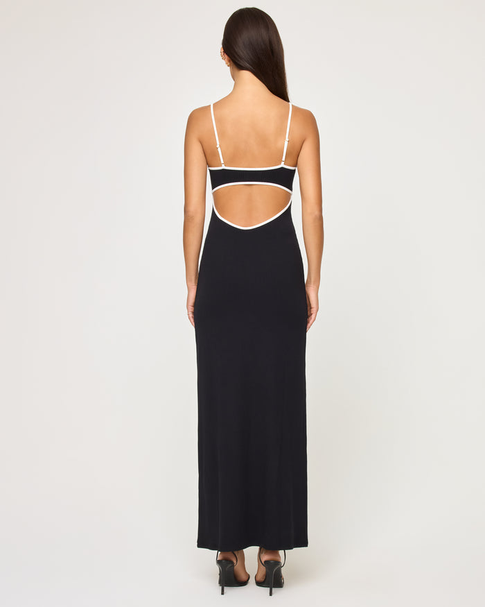 Back view of a model wearing the LSPACE Jordana Dress in black-cream, showing the open-back design with cream contrast trim and thin adjustable spaghetti straps.