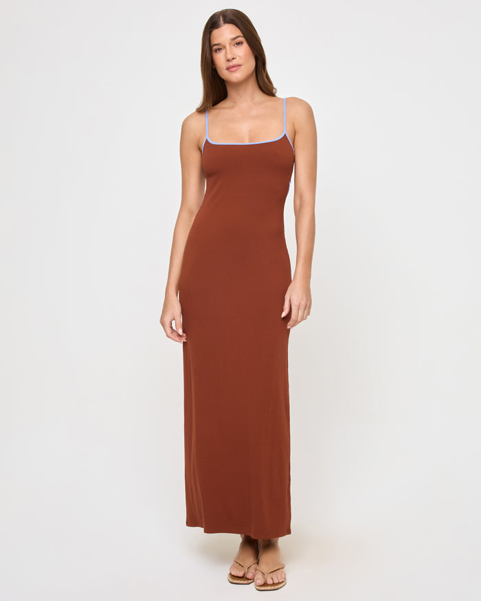 Full-length front view of a model wearing the LSPACE Jordana Dress in tobacco peri blue, a fitted maxi dress in a rich tobacco brown with thin spaghetti straps and periwinkle blue contrast trim along the scoop neckline.