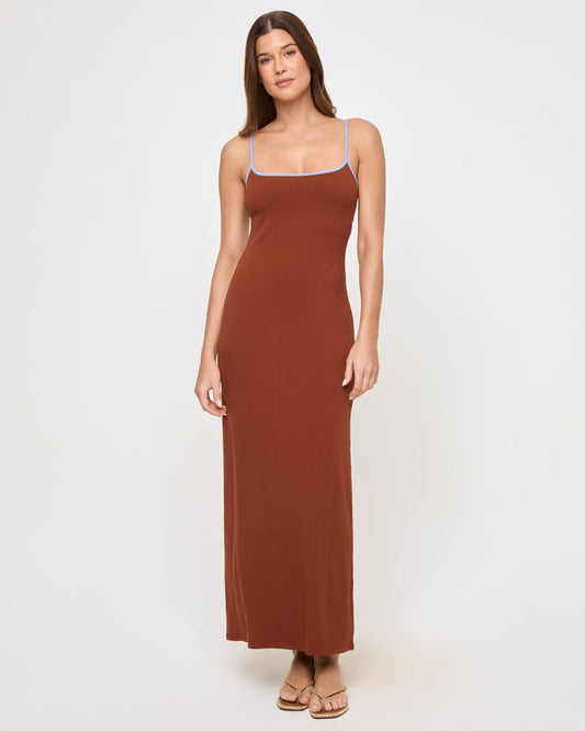 Full-length front view of a model wearing the LSPACE Jordana Dress in tobacco peri blue, a fitted maxi dress in a rich tobacco brown with thin spaghetti straps and periwinkle blue contrast trim along the scoop neckline.