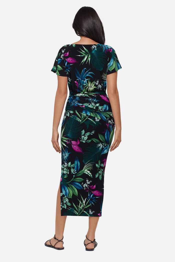 Woman faced away wearing a multicolored tropical printed short sleeve full length dress