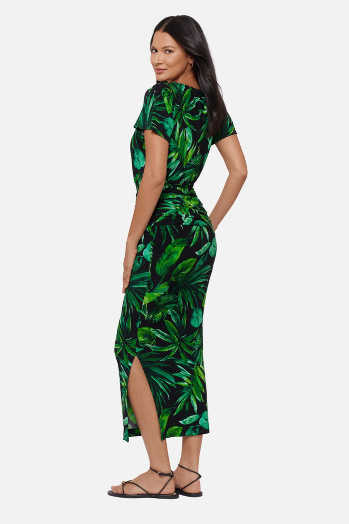 Woman turned left wearing a green palm leaf printed short sleeve full length dress