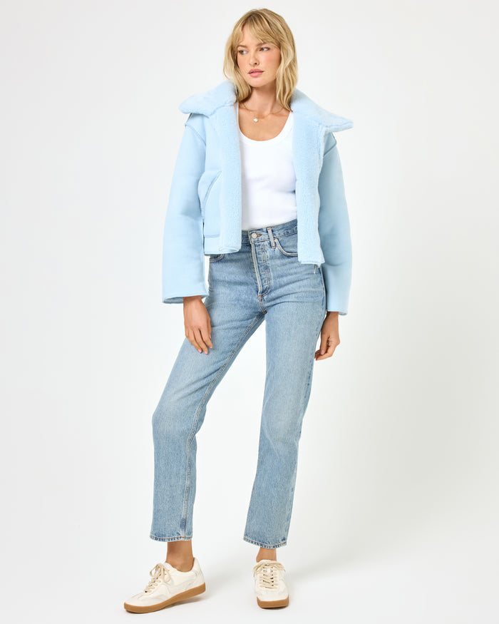 Full body front view of a model wearing the LSPACE Kalina Jacket in ice blue, styled with jeans and white sneakers, featuring the cropped boxy silhouette with wide sherpa collar and zip-front closure.