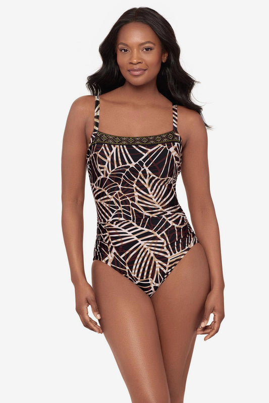 Woman wearing a brown abstract printed one-piece swimsuit with a detailed pattern on the neckline