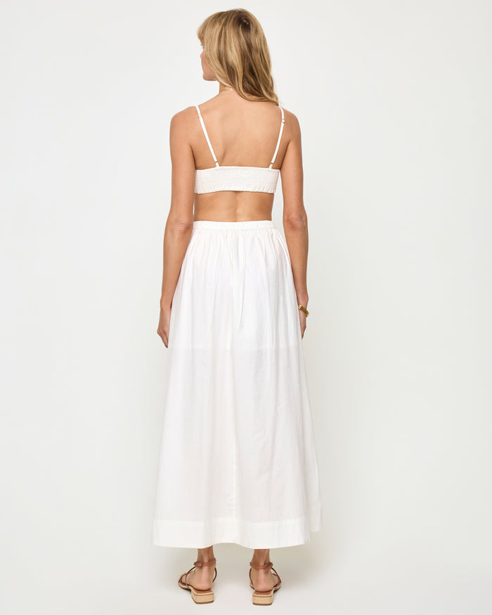 Back view of a model wearing the LSPACE Keeper Skirt in white, showing the full-length A-line silhouette and contrast hem trim.