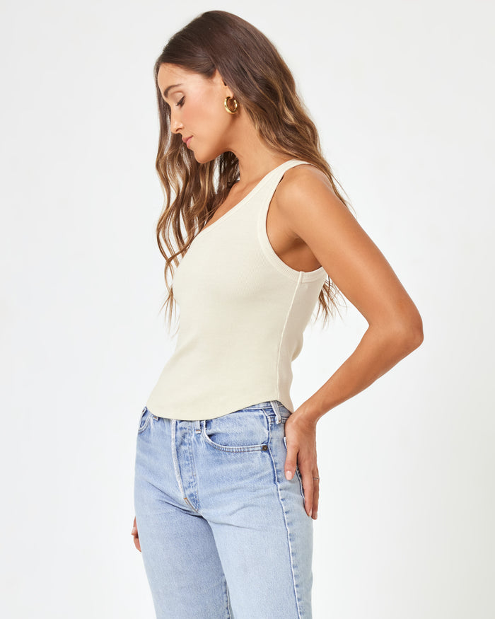 Side view of a model wearing the LSPACE Kylie Tank in bone, showing the one-shoulder neckline and fitted ribbed silhouette of the off-white crop tank.