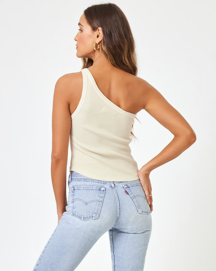 Back view of a model wearing the LSPACE Kylie Tank in bone, showing the asymmetric one-shoulder back and bare shoulder of the off-white ribbed crop tank.