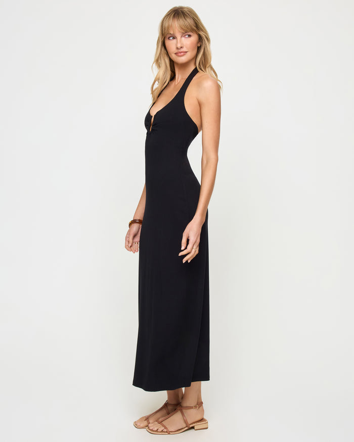 Side view of a model wearing the LSPACE La Femme Dress in black, showing the sleek fitted silhouette and halter neckline.