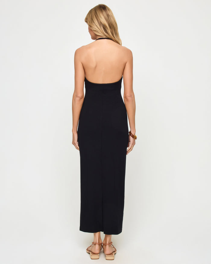 Back view of a model wearing the LSPACE La Femme Dress in black, showing the low open back and halter neck tie closure.