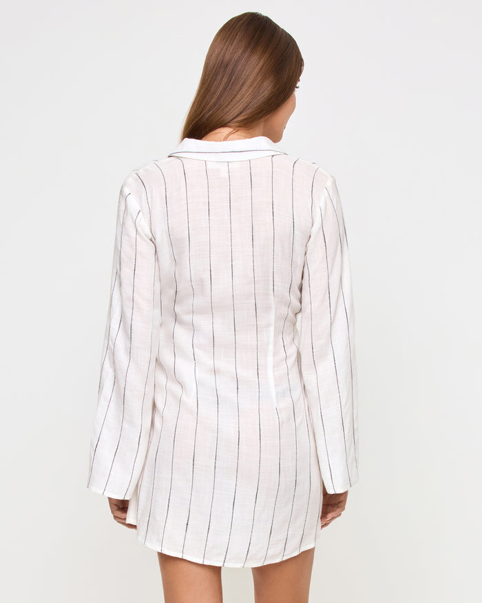 Back view of a model wearing the LSPACE Las Palmas Dress in fine line stripe, showing the wrap-style back with fine vertical stripes and long flared sleeves.