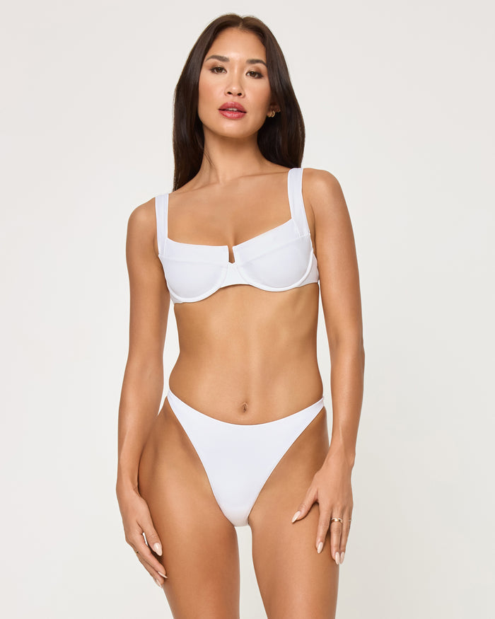 Front view of a model wearing the LSPACE white Leilani Bikini Bottom with a high-cut leg, paired with a white Mako Bikini Top.