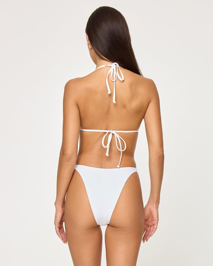 Back view of a model wearing the LSPACE white Leilani Bikini Bottom with a high-cut leg and cheeky coverage, paired with a white halter tie bikini top.