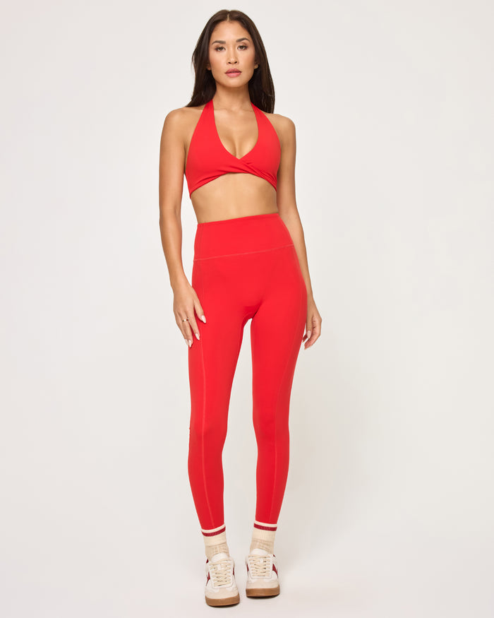 Front view of model wearing the Level Up Legging in flame with matching flame Jeanne Bra, striped socks and sneakers.