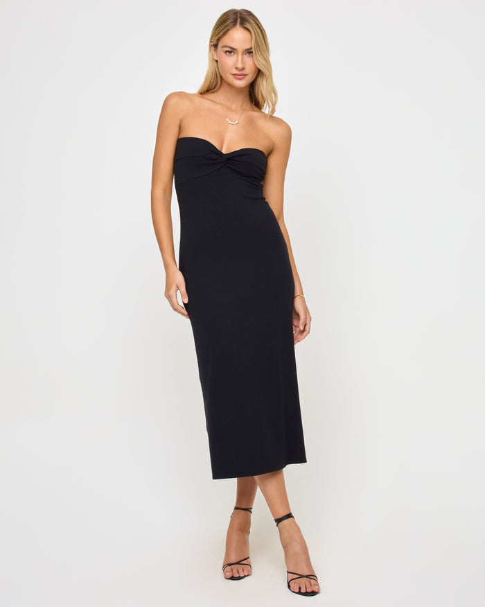 Front view of a model wearing the LSPACE Lisette Dress in black, a midi-length strapless dress with a twisted sweetheart neckline and fitted silhouette.