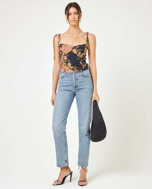 Front view of a model wearing the LSPACE Lottie Top in through thick and thorns, a dark floral corset-style crop top with spaghetti straps, paired with black wide-leg trousers.
