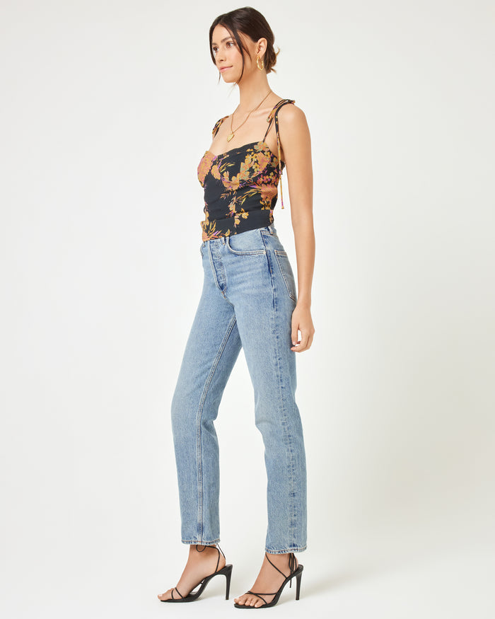 Side view of a model wearing the LSPACE Lottie Top in through thick and thorns, showing the floral corset crop top with spaghetti straps, paired with blue jeans and strappy heels.