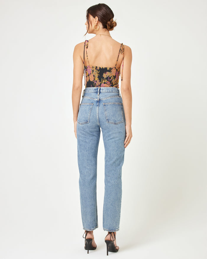 Back view of a model wearing the LSPACE Lottie Top in through thick and thorns, showing the open low back of the dark floral corset crop top, paired with blue jeans.