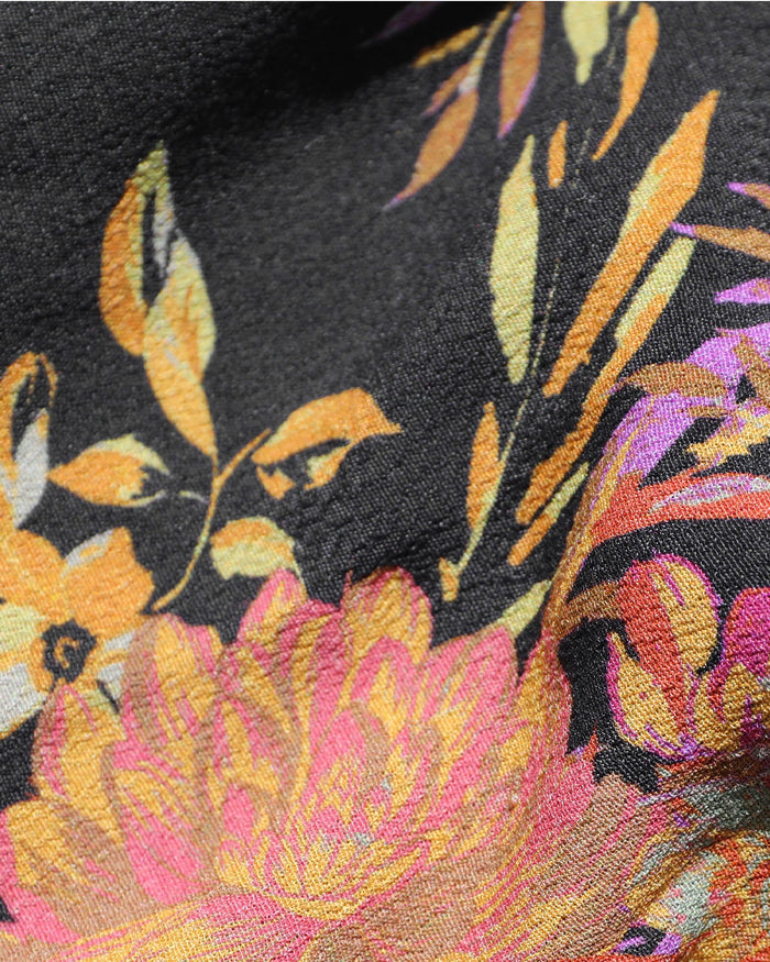 Close-up of the LSPACE Lottie Top in through thick and thorns, showing the floral print detail with a dark background and large orange, yellow, pink, and purple flowers and leaves.