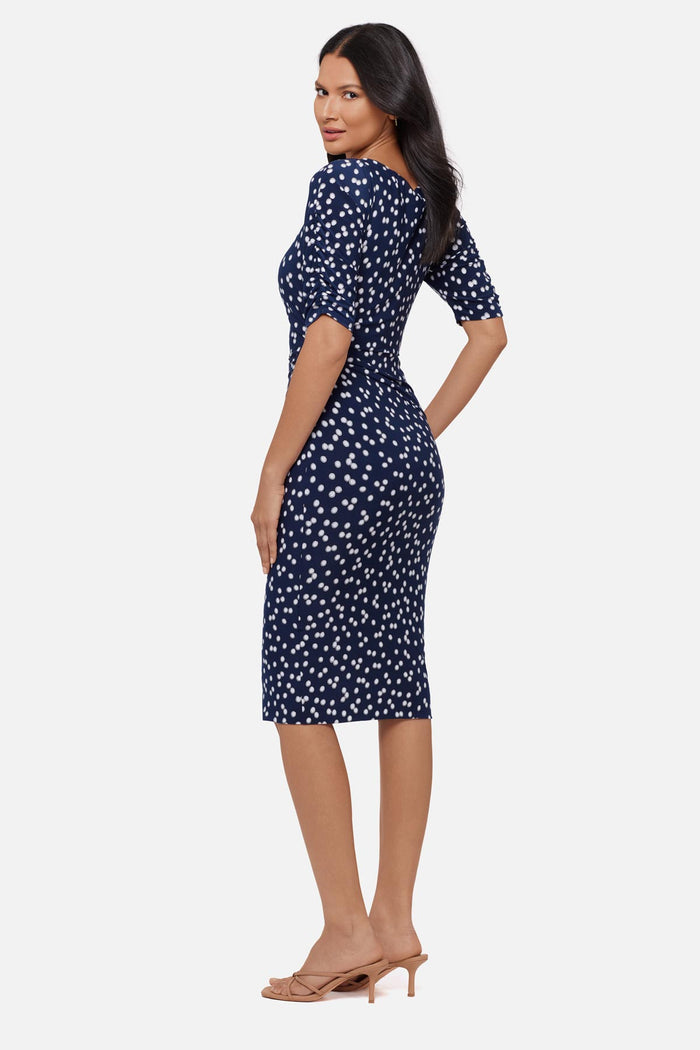 Woman faced left wearing a dark blue and white polka dot half sleeve mid length dress