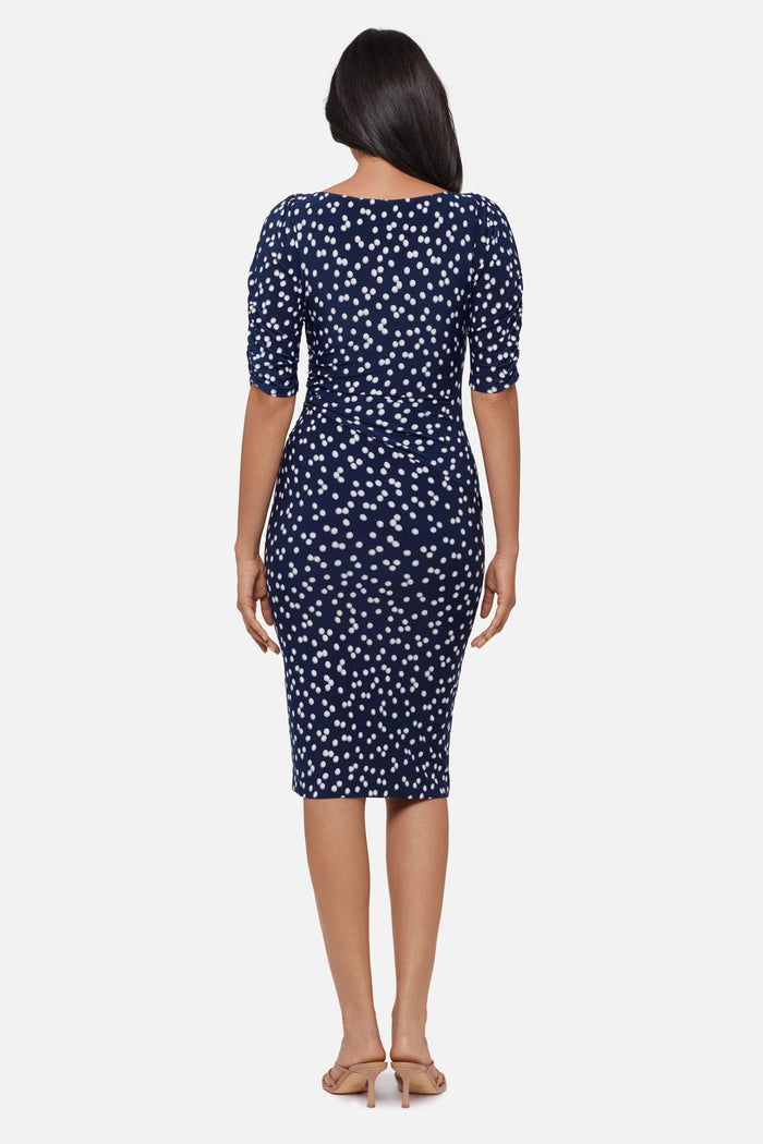 Woman faced away wearing a dark blue and white polka dot half sleeve mid length dress
