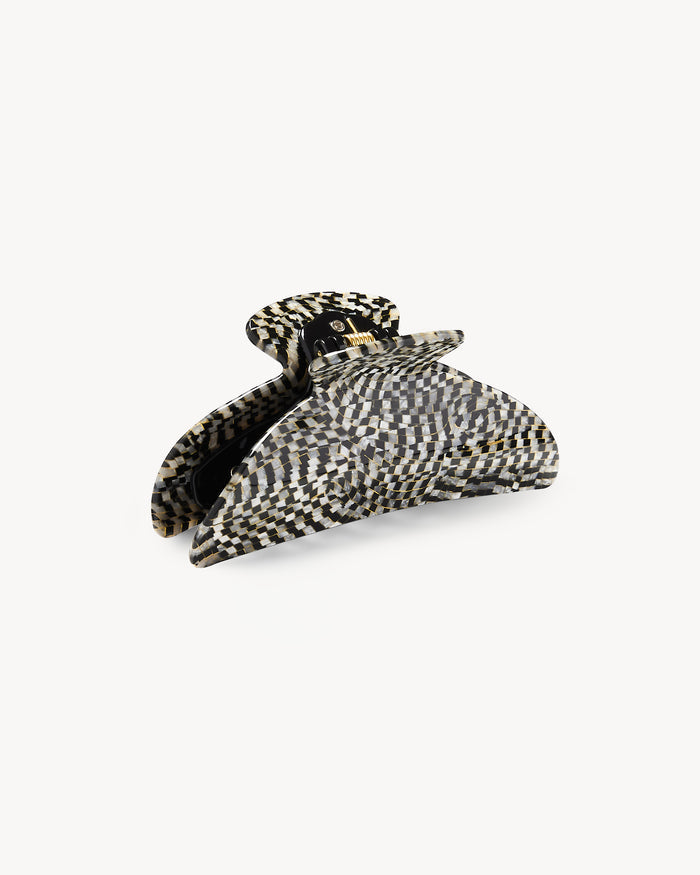 Off-model detail view of the Machete Midi Claw in perle noir shown open, displaying the black and white checkerboard pattern and gold hardware hinge.