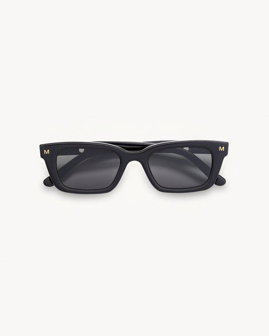 Off-model image of the Machete Ruby Sunglasses in black, folded flat with a black acetate rectangular frame and dark grey lenses.