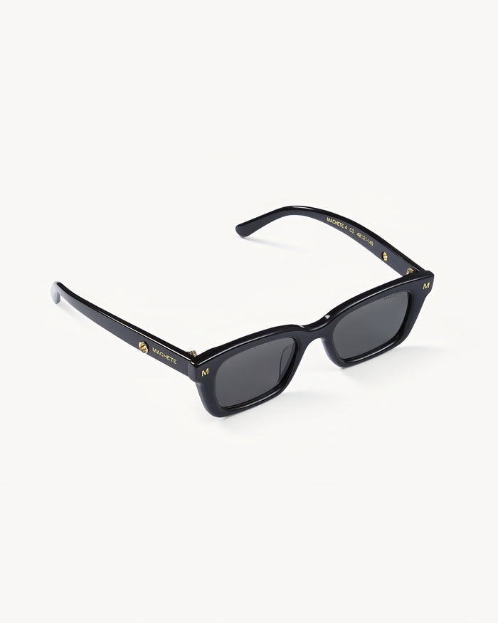 Off-model angled view of the Machete Ruby Sunglasses in black showing the rectangular frame and dark grey lenses.