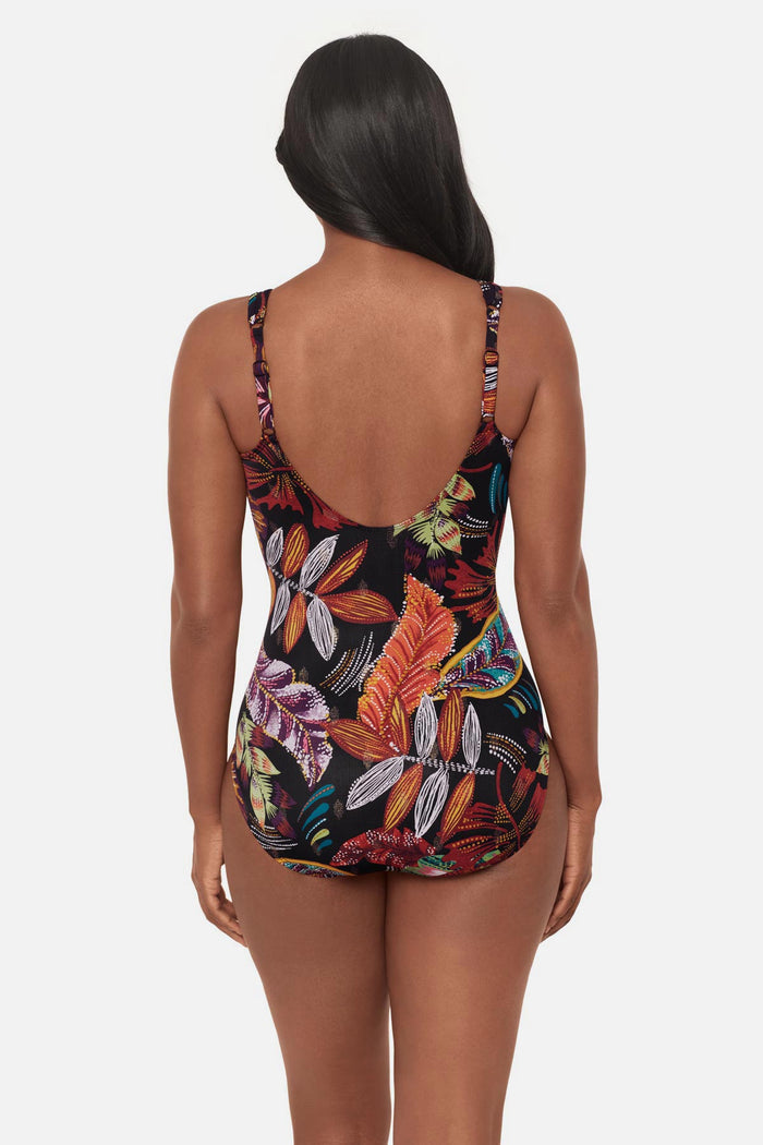 Woman faced away wearing a multicolored floral printed one-piece swimsuit with mesh cutouts