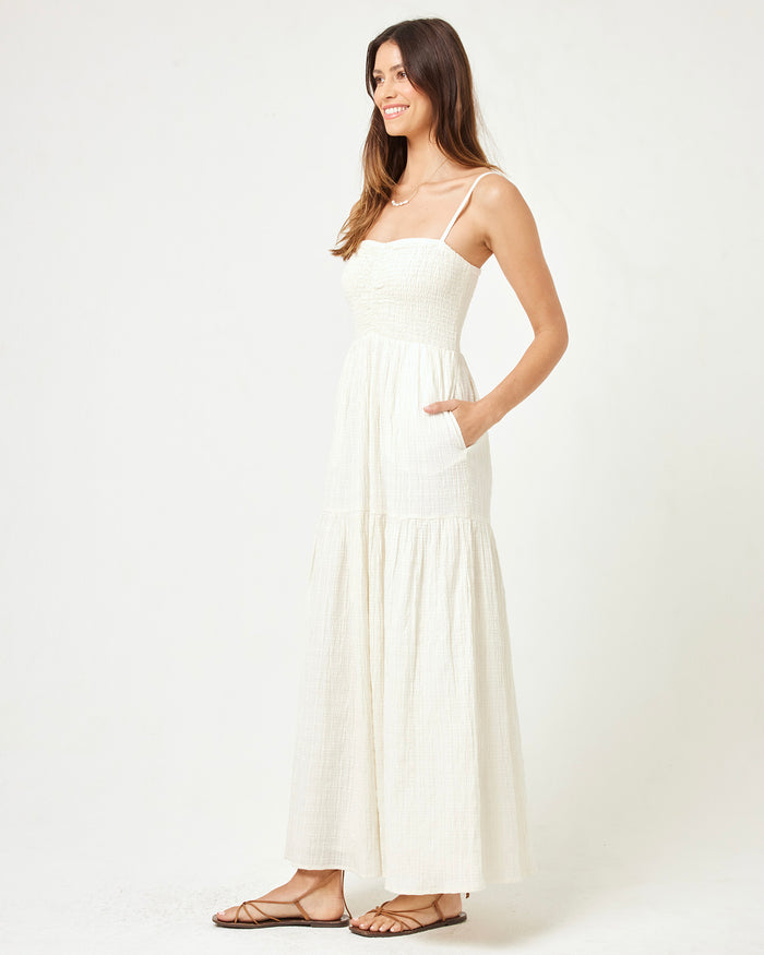 Side view of a model wearing the LSPACE Mallorca Dress in cream, showing the tiered maxi skirt, smocked bodice, and side pocket of the cream textured dress.
