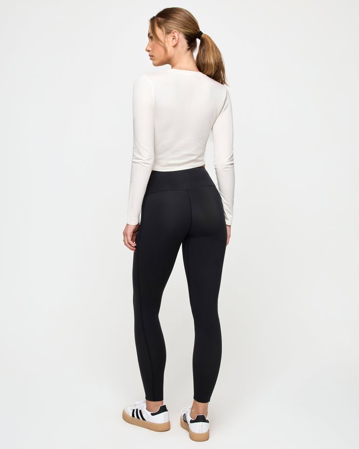 Back view of a model wearing the LSPACE Marseille Top in cream, a long-sleeve cropped top with a smooth fitted back.