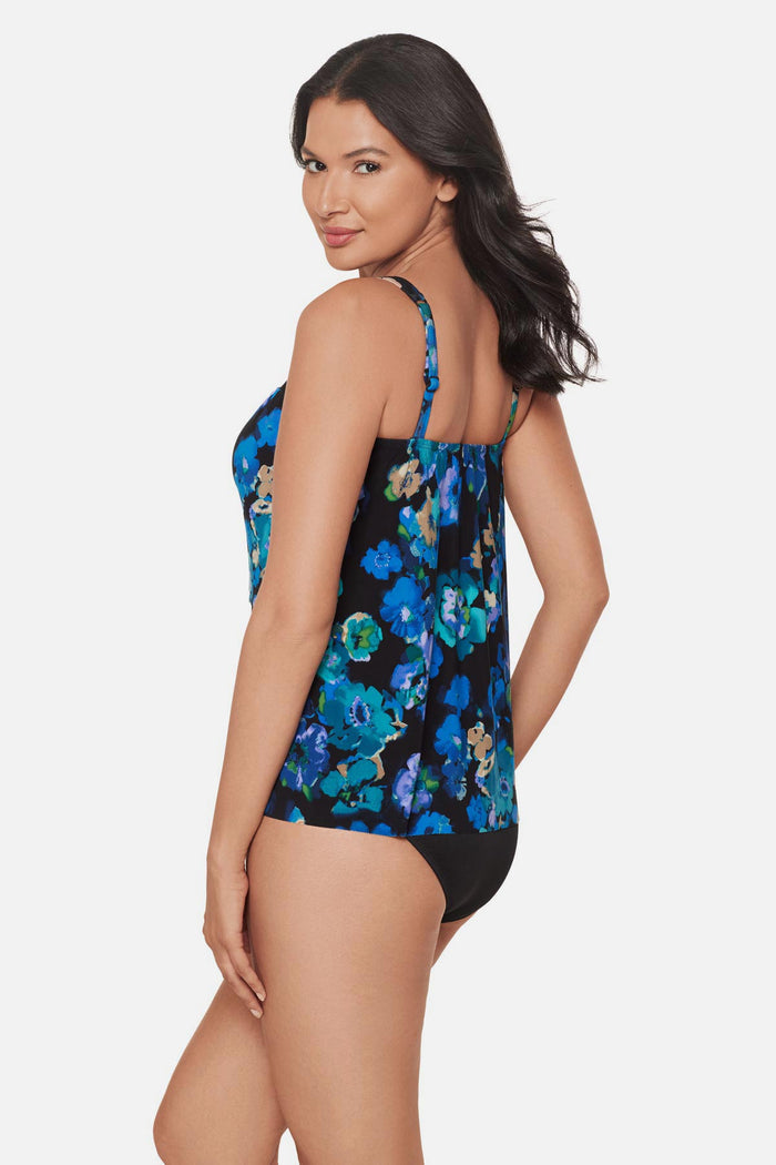 Woman turned left wearing a black and blue floral printed tankini top with mesh details