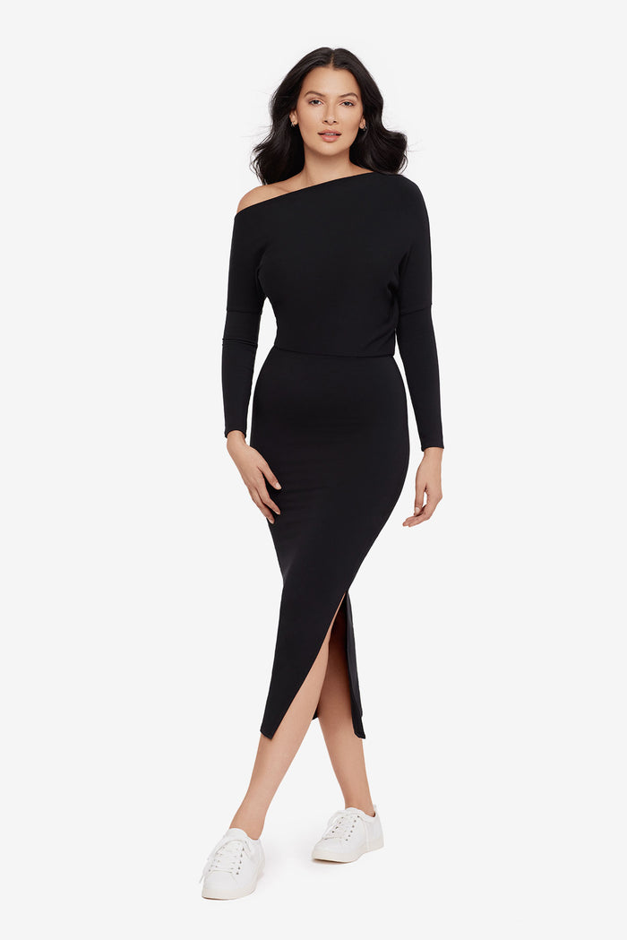Woman wearing a black asymmetrical off the shoulder long sleeve dress with side slit