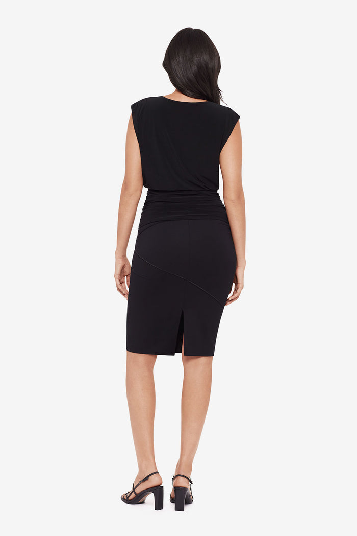 Woman turned away wearing a black tunic blouse with matching pencil skirt