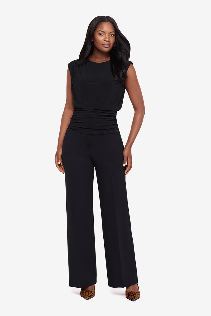 Woman in a black high neck blouse with matching wide leg pants