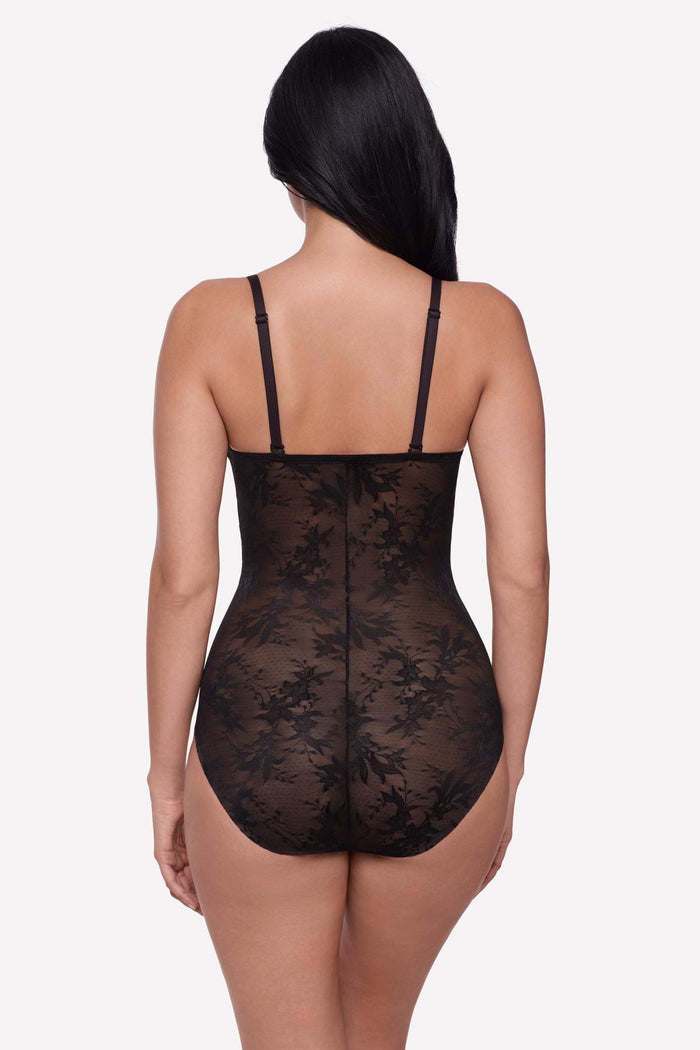 Woman faced away wearing a black lacey one-piece bodysuit