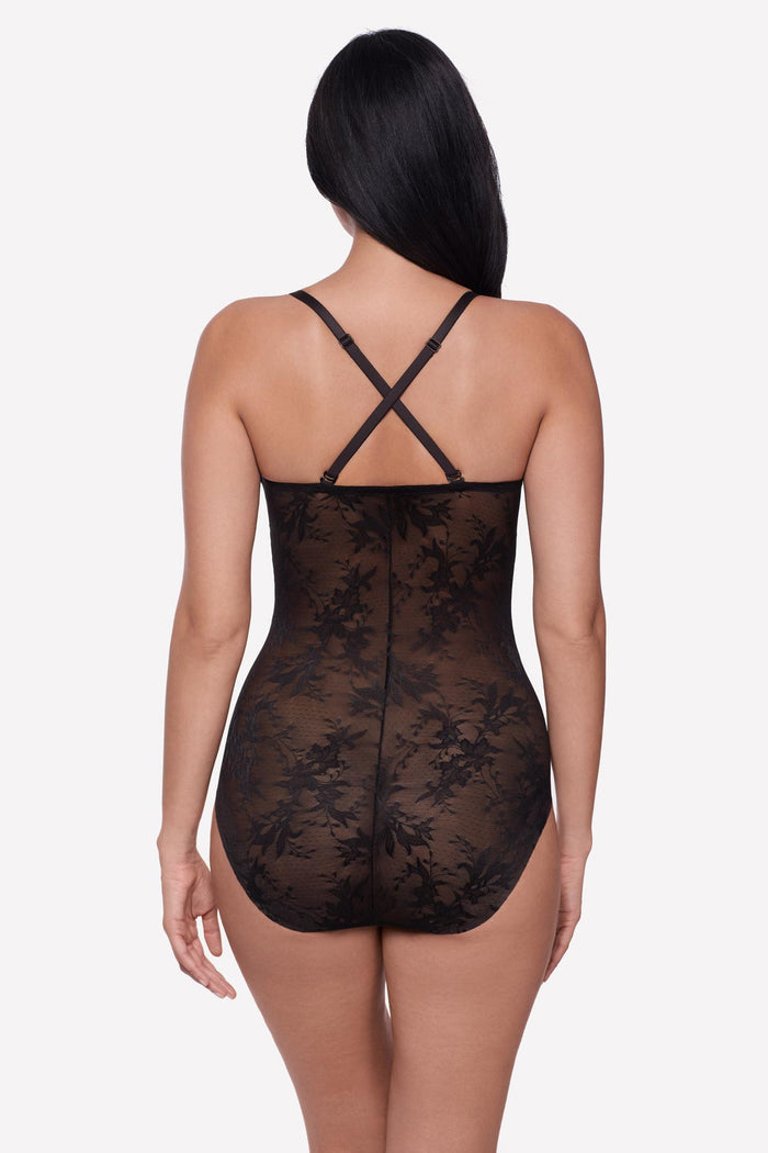 Woman faced away wearing a black lacey one-piece bodysuit with X back