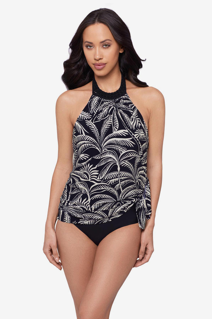 Woman wearing a black and white palm leaf printed swim dress with a tie on the side