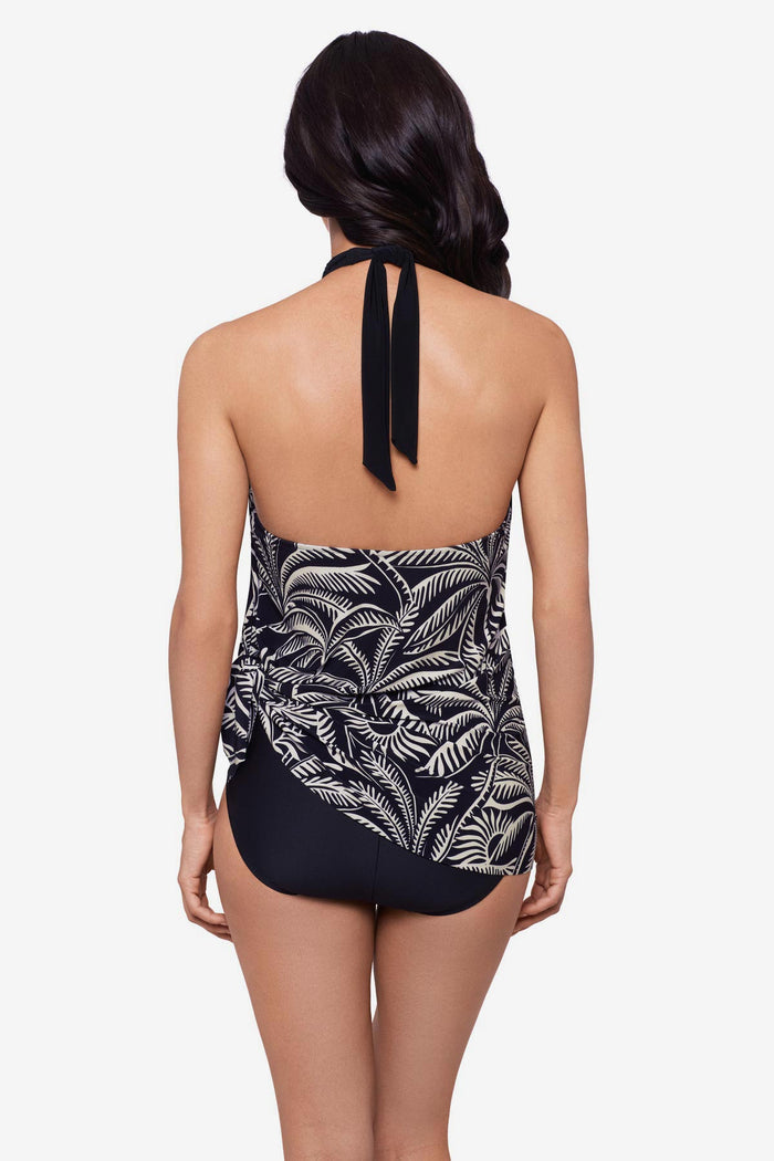 Woman turned away wearing a black and white palm leaf printed swim dress with a tie on the side