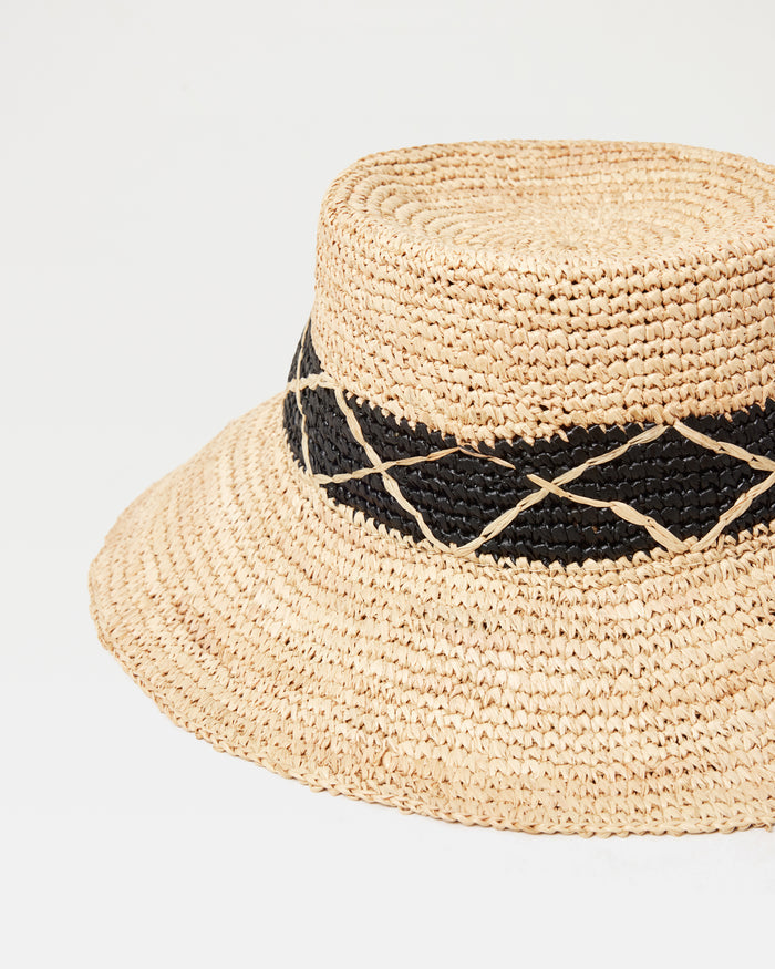 Close-up of the Montauk Bucket Hat in natural showing the woven raffia texture and black diamond-patterned band detail.