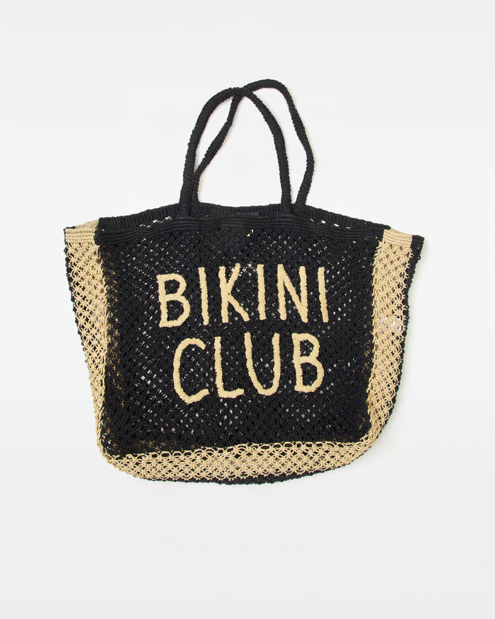 Off-model front view of the Moonlight Bag in natural-black, a large open-weave crochet tote bag with 'Bikini Club' intarsia lettering in natural on a black ground, with black rope handles, on a white background.